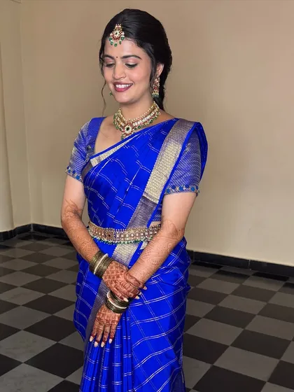 A full-length view of the bride in her stunning blue silk saree. The simple, elegant braid allows the beauty of the saree and her jewellery to shine.