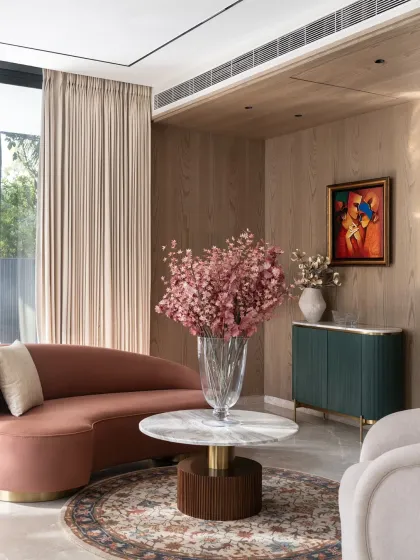 A different angle of the Bhasin foyer, highlighting the gracefully curved terracotta sofa and its interplay with the natural light from the adjacent window.