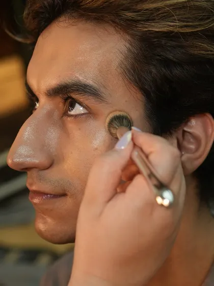 Our artists are trained in male grooming as well. Here, a student applies subtle makeup to a male model for a clean, camera-ready finish.