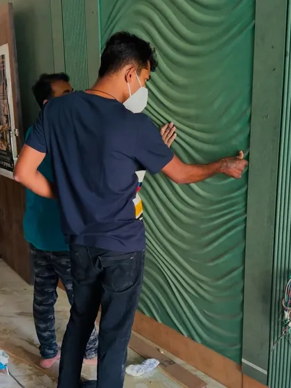 My team carefully installing the textured green wall panels, ensuring a perfect fit and finish.