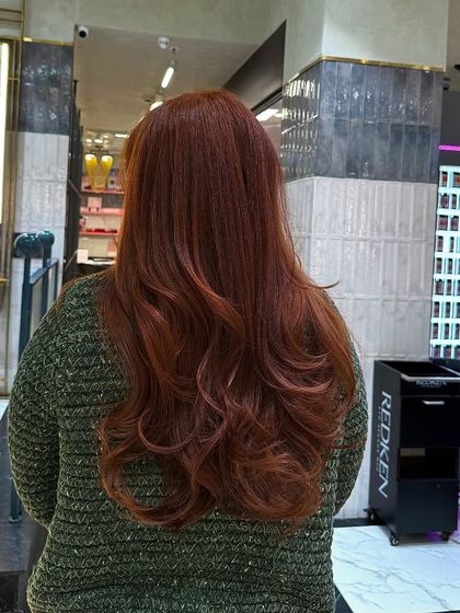 The final result of the amber hair transformation. The color is warm, rich, and has beautiful dimension, styled with soft waves.