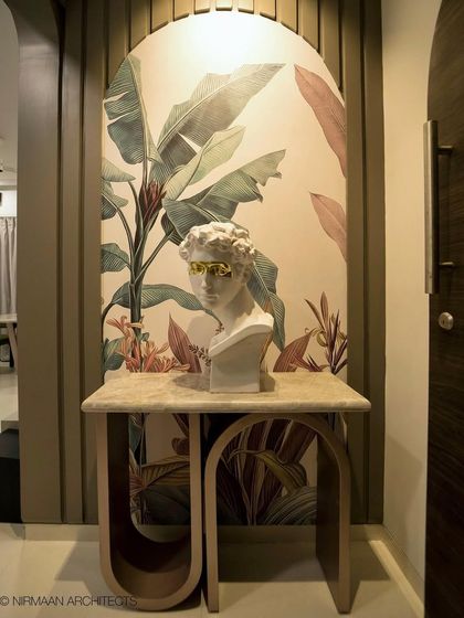 A quirky and artistic foyer design, featuring a classical bust set against a bold, tropical wallpaper. This entrance is designed to be a conversation starter.