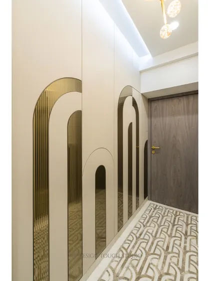 A close-up of the arched wall panels with fluted bronze mirror details. This shot showcases our attention to intricate, custom design elements that elevate a simple corridor into a statement space.