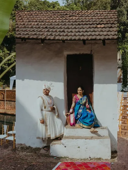 A portrait of the couple seated on the steps of a traditional Goan house, blending cultural heritage with their wedding story.