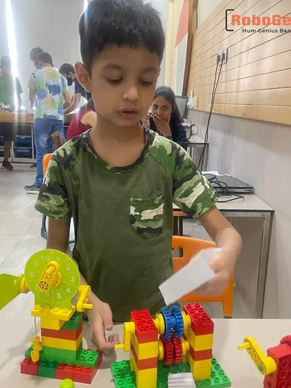 A young student from our Gurgaon center explains his LEGO creation, which uses a system of gears to power a fan. This hands-on activity is a core part of our STEM curriculum for early learners.