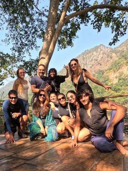 A happy group photo on a wooden deck overlooking the mountains. The shared adventure and stunning scenery bring us closer together as a community.