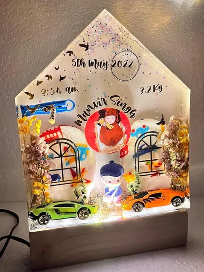 The house-shaped preservation block with the LED lights on, making it a perfect night light for a nursery.