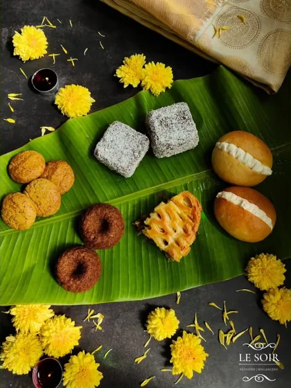A glimpse of my 'Nandi 2024' Onam collection, a special menu created to thank my wonderful Malayali clients. This spread on a banana leaf shows the variety, including Lamingtons, Butter Buns, and Unniappam-inspired cakes.