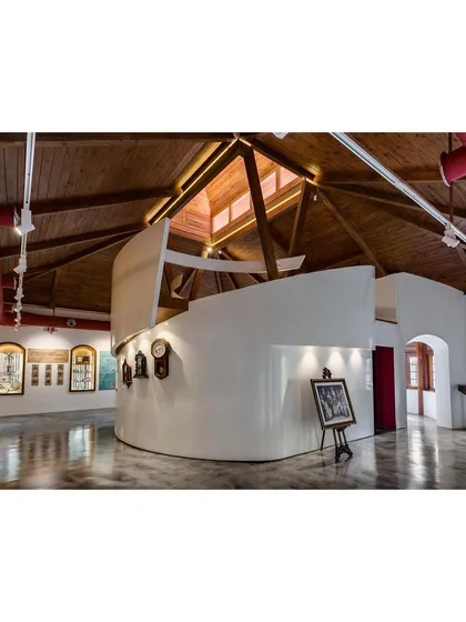 The interior of the restored museum, where a new central armature was inserted to organize the exhibition space. This curved wall guides circulation and creates a dynamic interplay with the original building's high, timber-clad ceilings.