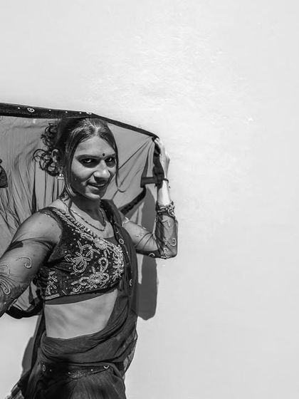 A woman in Bihar playfully lifts her veil, looking towards the camera with a gentle smile in a simple yet elegant black and white portrait.