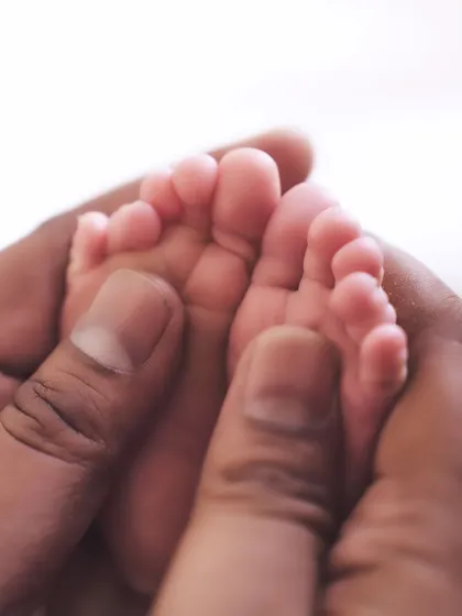 A close-up of a newborn's tiny feet held gently in a parent's hands. This photo is a timeless reminder of the delicate beginnings of a new life.
