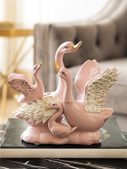 This family of dancing swans, finished in a lovely pastel pink with white and gold wings, is a beautiful representation of grace and family bonds. It's a perfect centerpiece for a coffee table.