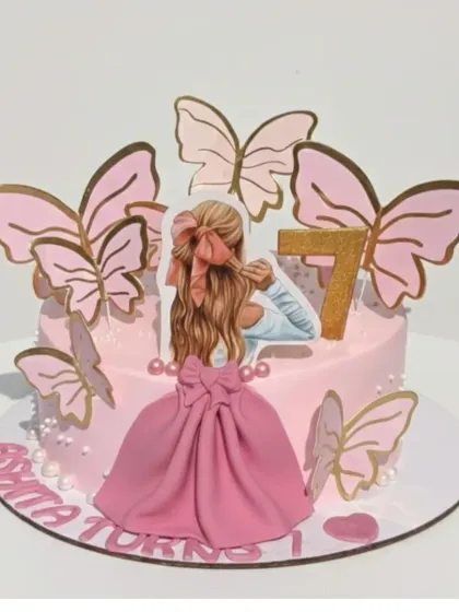 A fairytale 7th birthday cake with a chocolate truffle flavor. This design features a beautiful topper, a flowing pink fondant skirt, and delicate pink and gold butterflies.