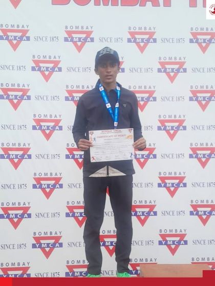 A young male athlete stands proudly on the podium after his performance at the Bombay YMCA athletics meet.