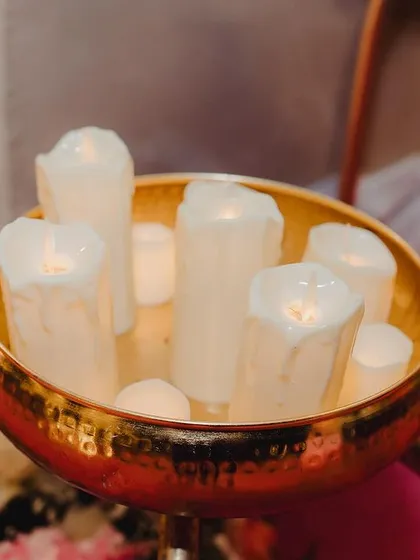 A closer view of the candle arrangement, with the pink floral carpet in the background. These small details contribute to the overall romantic and dreamy feel of the event.