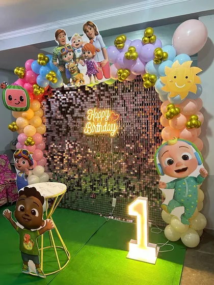 This angle highlights the character cutouts and the colorful balloon arch against the sparkling sequin backdrop.