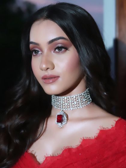 A close-up of a glamorous cocktail look with a diamond and ruby choker. The makeup features a soft red-toned smokey eye.
