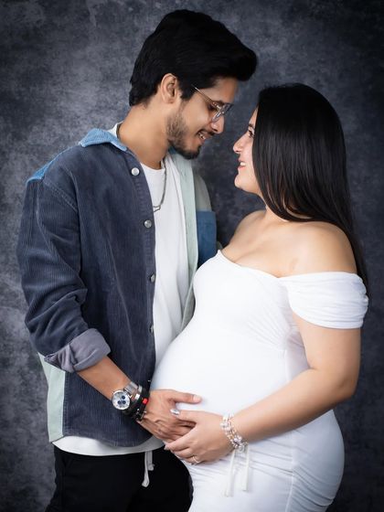 A modern and sweet couple's portrait. This young couple shares a loving look in our studio, dressed in contemporary outfits against a classic backdrop.