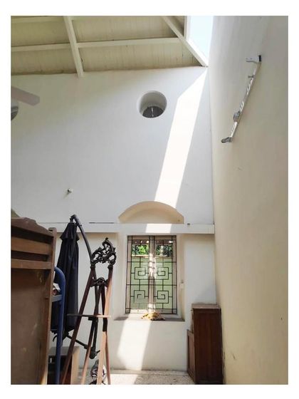 A view of an interior corner during renovation, showing the high ceilings and the interplay of light from a circular window. Even in its unfinished state, the unique architectural details of the building are prominent.