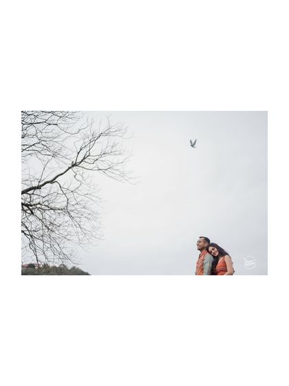 A minimalist composition showing the couple against a vast, open sky in Mussoorie. This artistic shot uses negative space to emphasize the couple's connection and the peacefulness of the mountain setting.