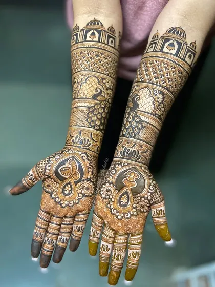 This design features majestic peacocks and architectural domes, creating a royal look. The intricate patterns and symmetrical layout are hallmarks of classic bridal mehendi.
