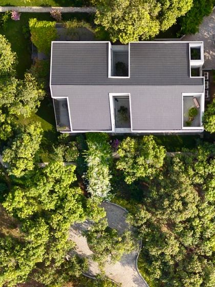 A top-down view reveals the geometric purity of the roof structure, with its clean lines and precisely cut openings for the internal courtyards. This showcases the architectural clarity of the design.