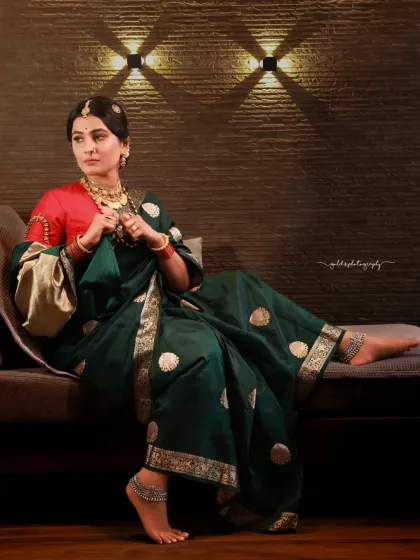 A full-length portrait showing the bride relaxing on a modern sofa. The contrast between the traditional attire and the contemporary setting creates a unique and stylish image.