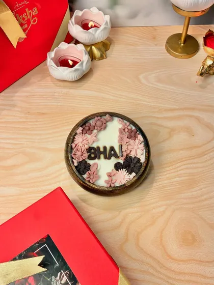 For the best brother, a special candle that says 'Bhai'. This personalized floral candle is set in a wooden bowl and makes for a thoughtful and unique Rakhi gift.