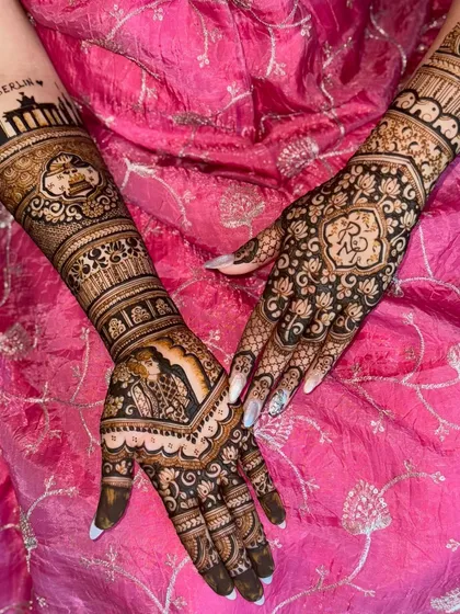 This back-of-hand design features a large, bold heart-shaped motif with the couple's initials. The surrounding floral patterns are delicate and intricate, creating a beautiful contrast.