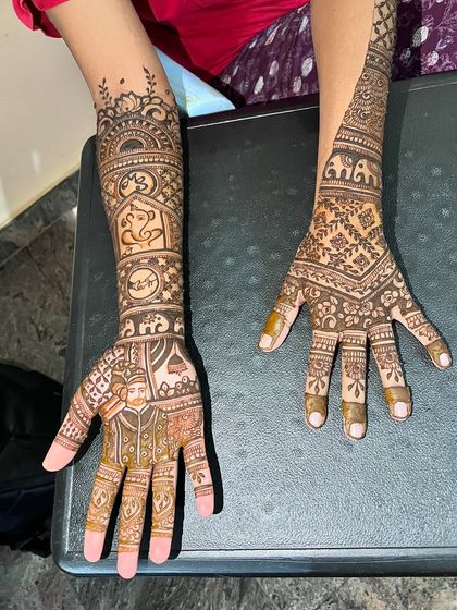 A view of both hands, one with the groom's portrait and the other with a complementary traditional design.