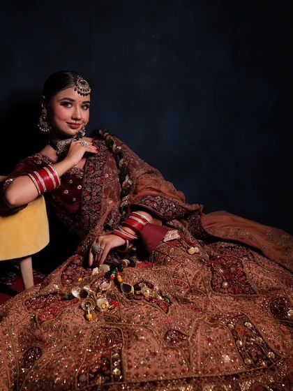 A full portrait of a bride in our maroon velvet lehenga. The rich fabric and detailed embroidery create a look of pure elegance, perfect for a winter wedding.