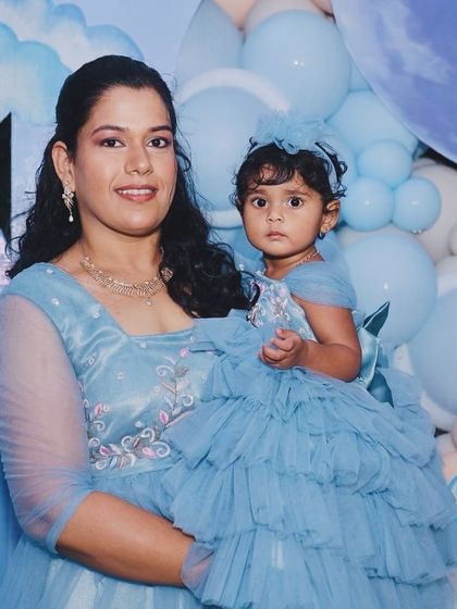 The birthday girl and her mother posing in front of the dreamy blue and white balloon backdrop.