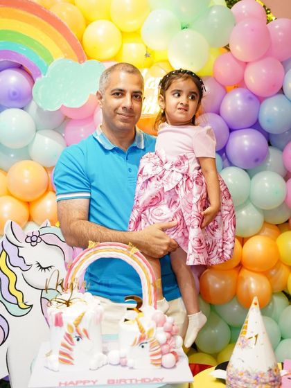 The birthday girl and her father pose by the stunning unicorn cake and rainbow backdrop. These are the family portraits you'll treasure forever.