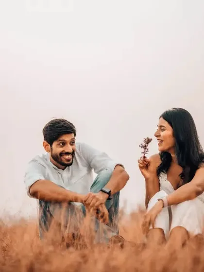A playful and sweet interaction between a couple sitting in a rustic field. These unposed, lighthearted moments make for the most memorable pre-wedding photographs.