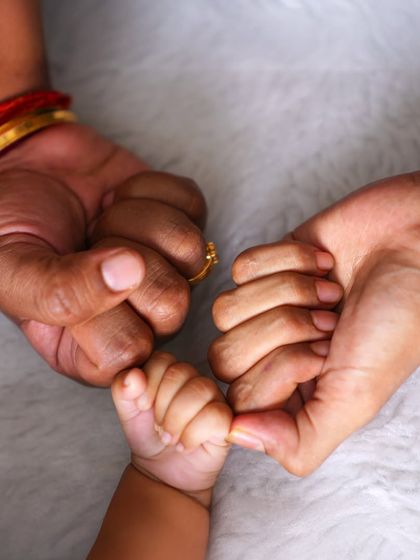 A powerful photo showing three generations of hands, as a baby's tiny hand grasps the fingers of their mother and grandmother.
