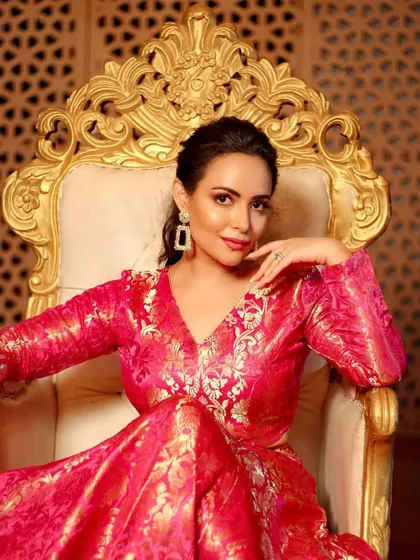 A close up portrait on the golden throne. Her expression is confident and serene, and the makeup, with its warm tones and radiant finish, looks absolutely flawless.