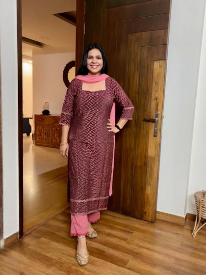 The same fabric as the previous image, but this time designed with a square neckline and paired with a contrasting pink dupatta and pants for a completely different look.