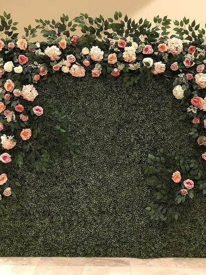 A classic and versatile backdrop, this green foliage wall is decorated with a beautiful arch of pastel roses, perfect for any elegant event.