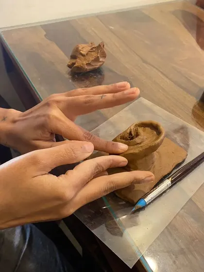 Hands carefully shaping the delicate curves of a clay ear. This tactile process is both meditative and challenging, offering a deep connection to the material and the subject.