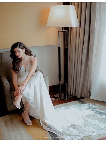 A full-length portrait of the bride seated, her elegant gown and long train beautifully displayed. This shot captures a moment of quiet grace before the ceremony.