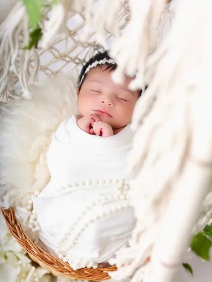 A beautifully framed shot of the sleeping newborn, peeking through the macrame details of the teepee. This creates a sense of intimacy and softness.