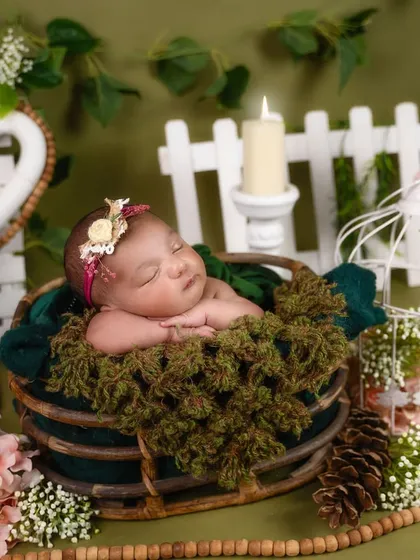 Another view of the rustic woodland theme, with a baby sleeping peacefully. The white picket fence and birdcage props add a charming, garden-like feel.