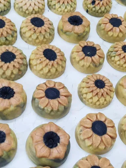 My Ubtan cold process soaps shaped like sunflowers. They are made with traditional ingredients like besan and turmeric, with activated charcoal for the center.