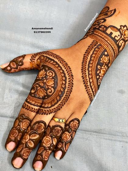 A unique back-of-hand design with large, circular floral motifs. The fingers are decorated with delicate rose patterns, and a small elephant adorns the wrist.