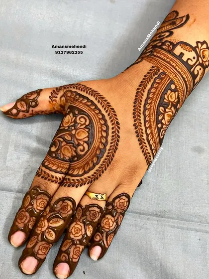 A unique back-of-hand design with large, circular floral motifs. The fingers are decorated with delicate rose patterns, and a small elephant adorns the wrist.