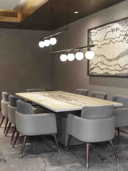 The informal dining area within the ground floor family lounge of the Bammi Residence. The space features a marble table with brass inlay, grey upholstered chairs, and artwork by Ganesh Selvaraj.