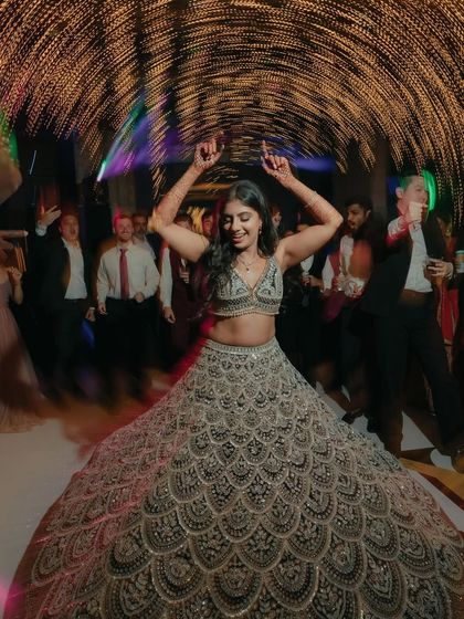 A moment of pure joy on the dance floor. The bride's wide smile and twirling lehenga, surrounded by motion-blurred lights, perfectly capture the energy and happiness of the reception.