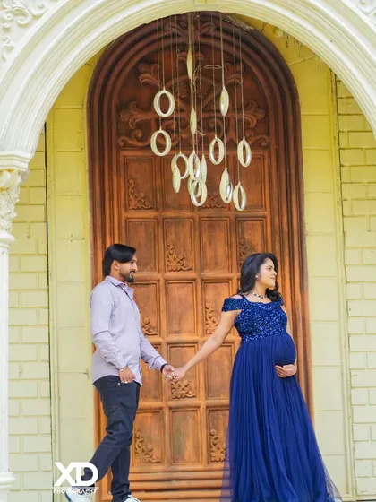 A romantic walking shot of a couple holding hands in front of a grand wooden door.