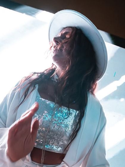 A dancer in a white hat and sequined top, embodying the chic vibe of the White Party. Thematic performers enhance the immersive quality of the event.