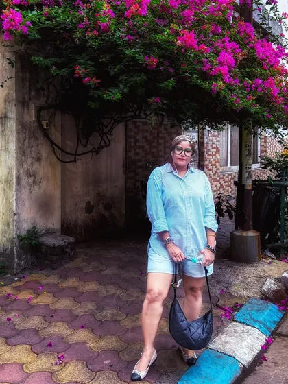 A full-length view of the outfit under the bougainvillea, showing the complete look with shoes and bag.
